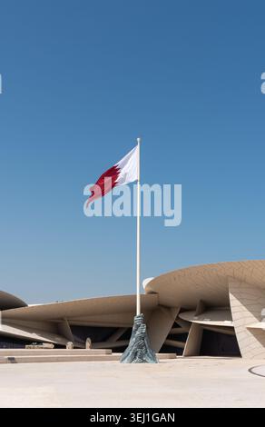 Doha, Katar - 14. Februar 2026: Vertikale Ansicht der Nationalflagge von Katar fliegt vor dem Nationalmuseum von Katar. Stockfoto