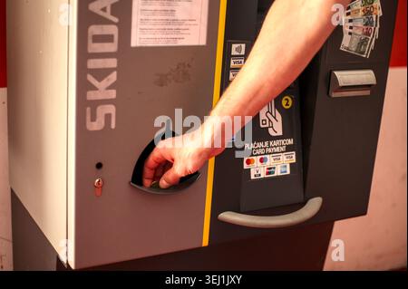 Die Hand des Mannes greift in die Münzrückgabetasche eines Skidata-Parkplatzes, um Geld zu sammeln, nachdem er für das Parken in Opatija bezahlt hat. Stockfoto