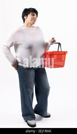 Eine junge Frau, die einen roten Warenkorb hält und lächelt Stockfoto