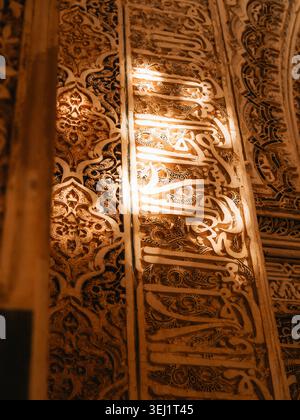 Blick auf komplizierte arabische Kalligraphie und geometrische Steinschnitzereien an den Wänden des Alhambra-Palastkomplexes in Granada, Andalusien, Spanien. Stockfoto