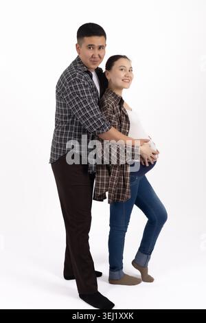Ein junger Mann umarmt eine schwangere Frau von hinten Stockfoto