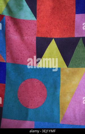 Farbenfrohes geometrisches Stoffmuster mit abstrakten Dreiecken, Quadraten und Kreisen in knalligen Rosa-, Blau-, Gelb- und Rottönen. Modernes Textildesign Stockfoto
