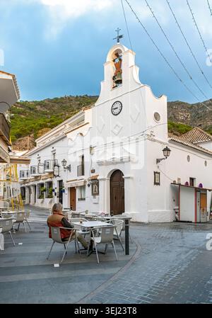 Blick auf die Straße auf die weiß getünchte Kirche San Sebastián mit Glockengiebel, mit Außenterrasse im Vordergrund, Mijas, Andalusien, Spanien Stockfoto