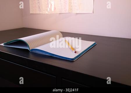 Bleistift liegt auf einem offenen Notizbuch auf einem Tisch Stockfoto