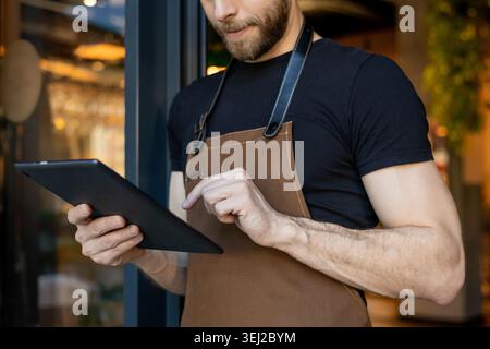 Der Barista hält das Tablet und tippt mit den Händen Stockfoto