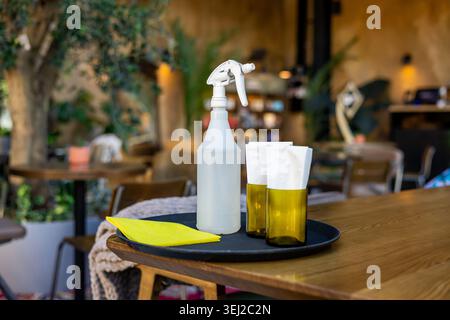 Desinfektionsspray Flasche und Servietten auf Tablett im Café Stockfoto