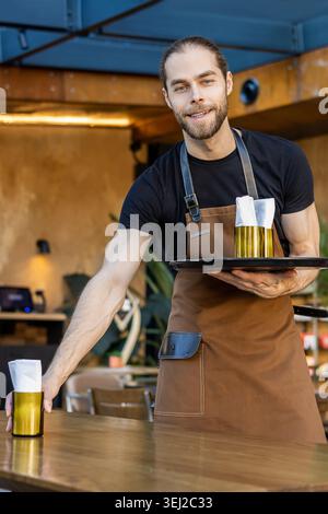 Porträt eines lächelnden Kellners, der einen Tisch im Café legt Stockfoto