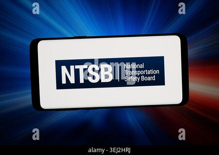 In dieser Fotoabbildung wird das Logo des National Transportation Safety Board (NTSB) auf einem Smartphone vor abstraktem Hintergrund auf dem Computerbildschirm angezeigt. Stockfoto