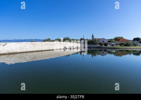 Nin, Kroatien, Dalmatien - 15. September 2025: Panoramablick von der Promenade Branimir auf die untere Nin-Brücke, das untere Stadttor aus Stein und die Altstadt Stockfoto