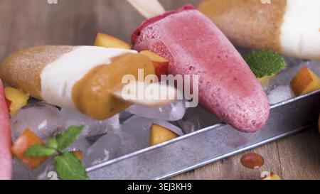 Hausgemachte Himbeeren und Pfirsicheiskel auf einem Holztisch Stockfoto
