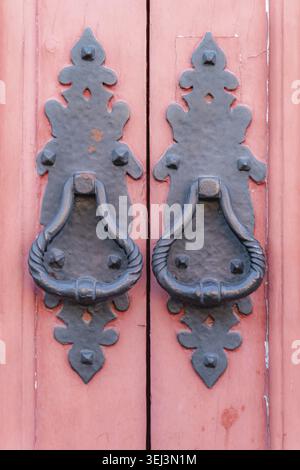 Vintage Metallic Türgriffe schwarz auf einem hölzernen rot lackierten hölzernen Türhintergrund, Konzept der authentischen Objekte, Kopierraum, Nahaufnahme Stockfoto