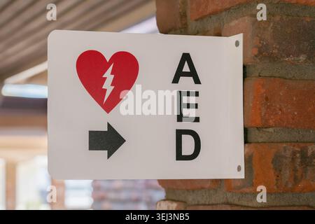Schild zur Positionierung des AED-NotfallDefibrillators an der Ziegelsäule angebracht Stockfoto