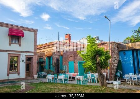 Ayvalik - Türkei, 17. Mai 2026, historisches Restaurant aus Stein mit türkisfarbenen Rollläden und Markisen auf Cunda Island Stockfoto