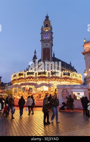 Weihnachtsmarkt Lille bei Nacht; Menschen und Karussell vor dem Chambre de Commerce, Grand Place oder Place du General de Gaulle, Lille France Stockfoto
