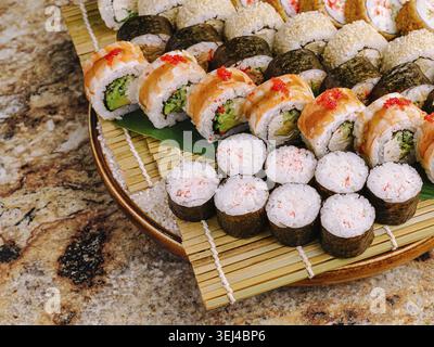 Essen, Eine bunte Auswahl an Sushi wird auf einer Holzplatte ausgestellt. Verschiedene Brötchen werden sorgfältig mit einer Mischung aus Meeresfrüchten, Gemüse und Rice angeordnet Stockfoto