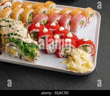 Essen, Eine lebendige Platte mit verschiedenen Sushi-Brötchen, ordentlich angeordnet. Zu den Höhepunkten gehören Lachs-, Thunfisch- und Krabbenbrötchen mit Saucen und Beilagen. Ide Stockfoto