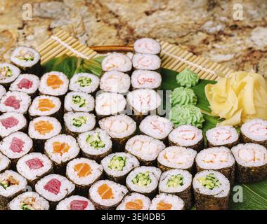 Speisen, Eine farbenfrohe Platte zeigt eine Auswahl an Sushi-Brötchen, darunter Thunfisch, Lachs und Gemüse. Das Sushi wird mit Wasabi und Pickl garniert Stockfoto
