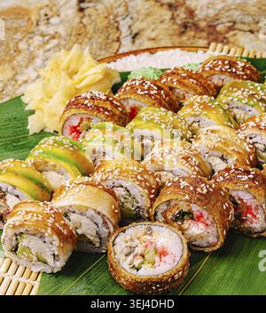 Essen, Eine große Platte enthält eine Auswahl an Sushi-Brötchen in verschiedenen Farben, einschließlich verschiedener Füllungen und garniert mit Ingwer auf einem Bamb Stockfoto