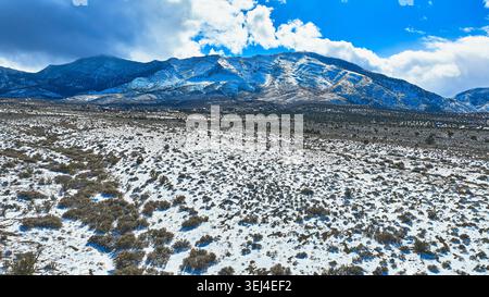 Luftschneebedeckte Wüstenebene und Mt. Charleston Peaks unter dramatischem Himmel Stockfoto