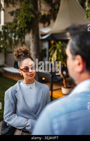 Frau mit Sonnenbrille, die draußen mit dem Mann spricht Stockfoto