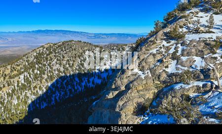 Aerial Snow Covered Mountain Ridge und Forest mit ausgedehnter Nevada Landschaft Stockfoto