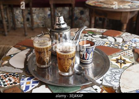 Traditionelle marokkanische Teekanne mit Gläsern auf einem dekorativen Mosaiktisch Stockfoto