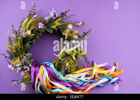Blumenkranz mit bunten Bändern auf lila Hintergrund Stockfoto