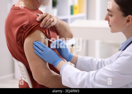 Krankenschwester in medizinischen Handschuhen impfend Mann im Krankenhaus, Nahaufnahme Stockfoto