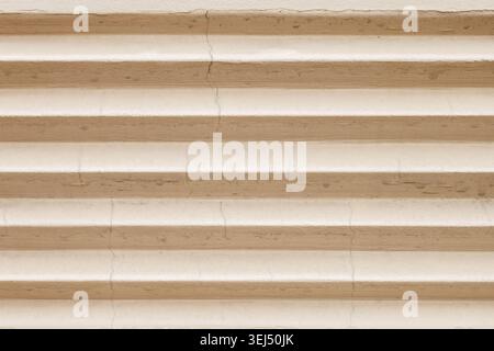 Beige gewellte Wandoberfläche mit vertikalen Rissen Stockfoto