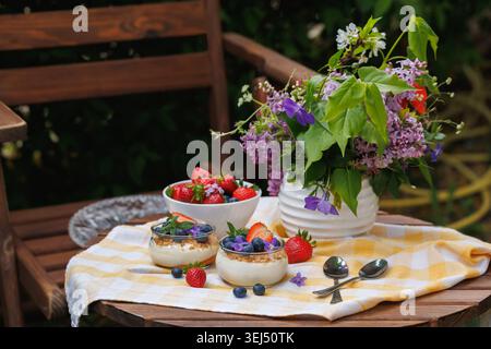 Sommer-Picknicktisch mit Beeren-Käsekuchen-Dessert und frischen Blumen Stockfoto