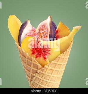 Frisches Obst in Waffelkegel auf salbeifarbenem Hintergrund Stockfoto