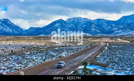 Aerial Snowy Road und Fahrzeug mit Mt. Charleston Peaks in der Nähe von Cold Creek Nevada Stockfoto