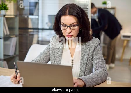 Konzentrierte Buchhalterin für Geschäftsleute, die in modernen Büros und Finanzgeschäften an Notebooks arbeitet Stockfoto