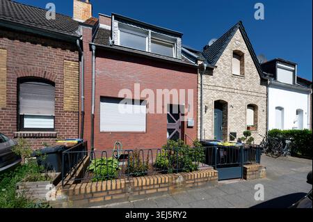 Eine Reihe traditioneller Kleinstädte in Köln-Bickendorf mit verschiedenen Backsteinstilen und modernen Renovierungsarbeiten unter blauem Himmel Stockfoto