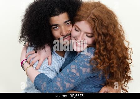 Glückliches junges, interrassisches Paar, das sich umschließt, einen engen und intimen Moment teilt Stockfoto