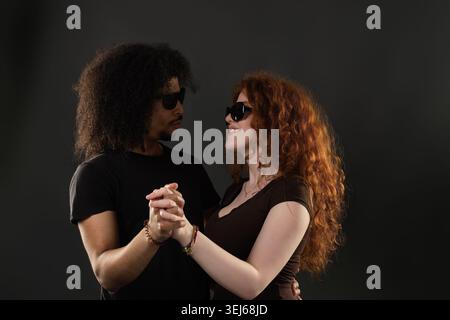 Verschiedene Paare tragen Sonnenbrille und tanzen, symbolisieren Liebe und Zweisamkeit Stockfoto