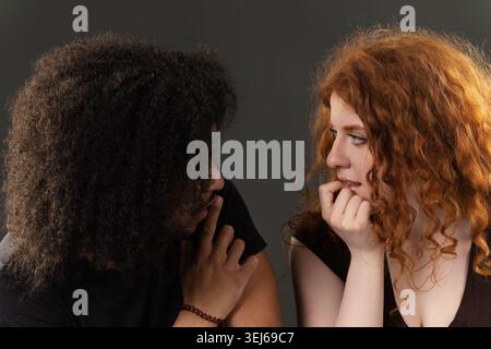 Verschiedene junge Paare, die sich anschauen, einer beißt Nägel, das andere berührt Lippen Stockfoto