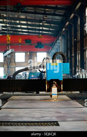 Eine Laserschneidemaschine für Lichtwellenleiter arbeitet in einer industriellen Werkstatt. Das Hauptgehäuse des Geräts ist blau-grün, und der Schneidkopf ist professionell Stockfoto