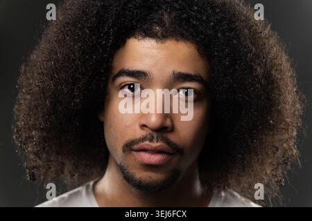 Junger Mann mit Afro-Frisur, der direkt in die Kamera schaut Stockfoto