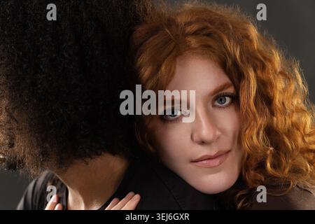 Rothaarige Frau, die Kopf auf der Schulter des Mannes liegt und ein Gefühl von Vertrauen und Sorgfalt schafft Stockfoto