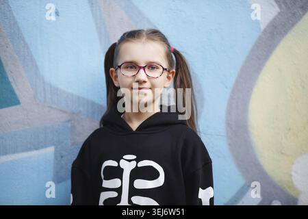 Porträt eines Mädchens im schwarzen Sweatshirt vor Wandhintergrund. Selektiver Fokus Stockfoto