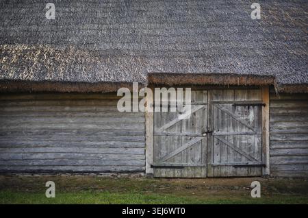 Alte Holzscheune. Holzwand, Tor und Strohdach Stockfoto