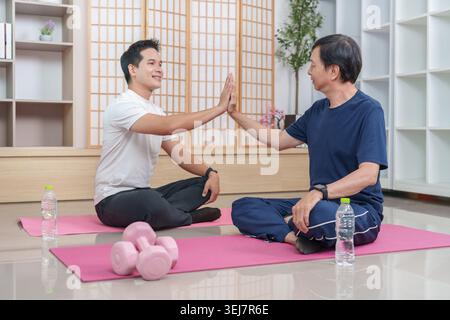 Asiatische Männer geben nach dem Heimtraining High 5 Stockfoto