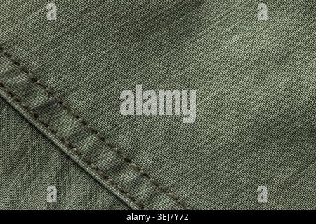 Großaufnahme aus olivgrünem Baumwollgewebe mit diagonaler Naht mit braunen Nähten, die die gewebte Textur und das Textildetail hervorheben, ideal für Hintergründe Stockfoto