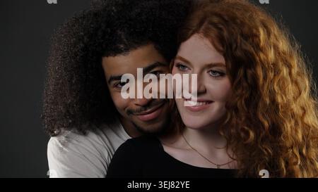 Liebevolles, interrassisches Paar, das sich umschließt, lächelt und sich glücklich fühlt Stockfoto