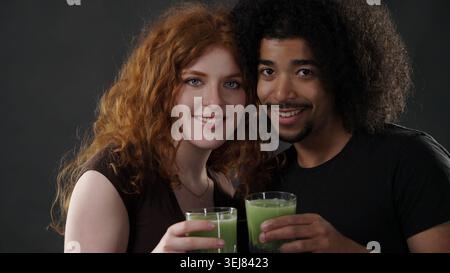 Glückliches Paar, das mit gesundem grünem Saft toast, um Wellness und Beziehung zu feiern Stockfoto