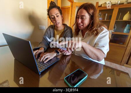Zwei Frauen diskutieren über Finanzdokumente und Rechnungen, arbeiten an Ausgaben und Haushaltsbudget zusammen, arbeiten in einem Home Office Stockfoto