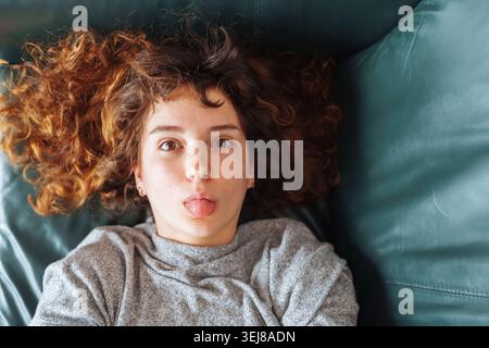 Junge rothaarige Frau, die sich auf einem Ledersofa entspannt Stockfoto