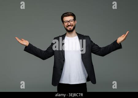 Junger Geschäftsmann mit Balance Hände isoliert auf grauem Hintergrund Stockfoto
