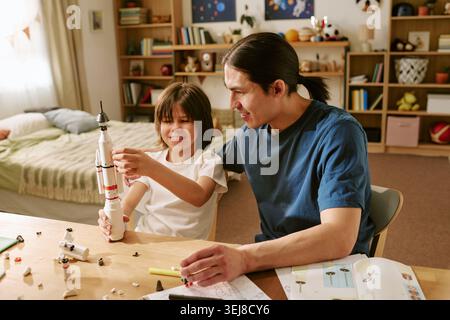 Asiatisches Vater und Sohn, das Raketenmodell für die MINT-Ausbildung zusammenstellt Stockfoto